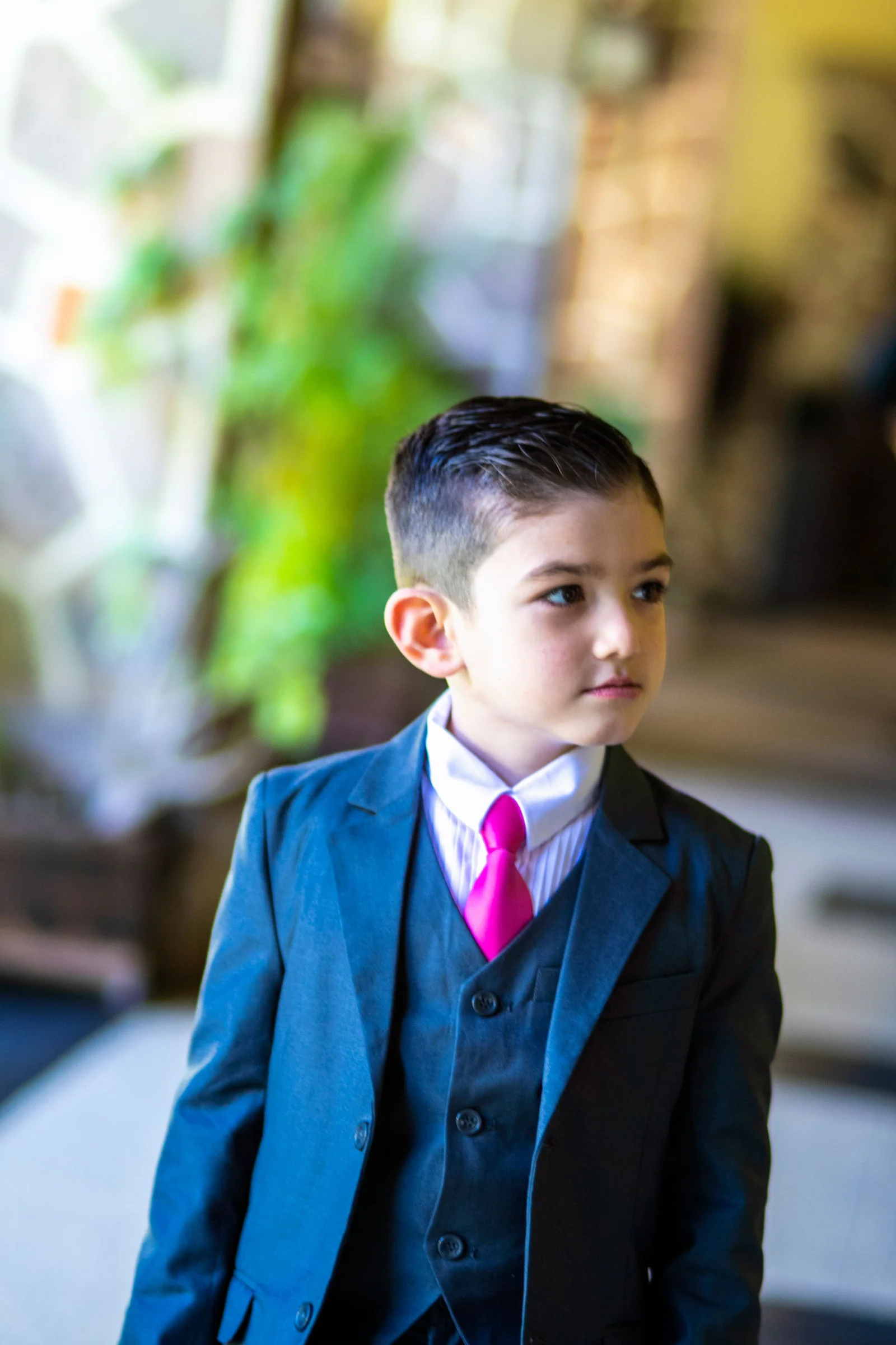 Young boy in a suit with pink tie indoors