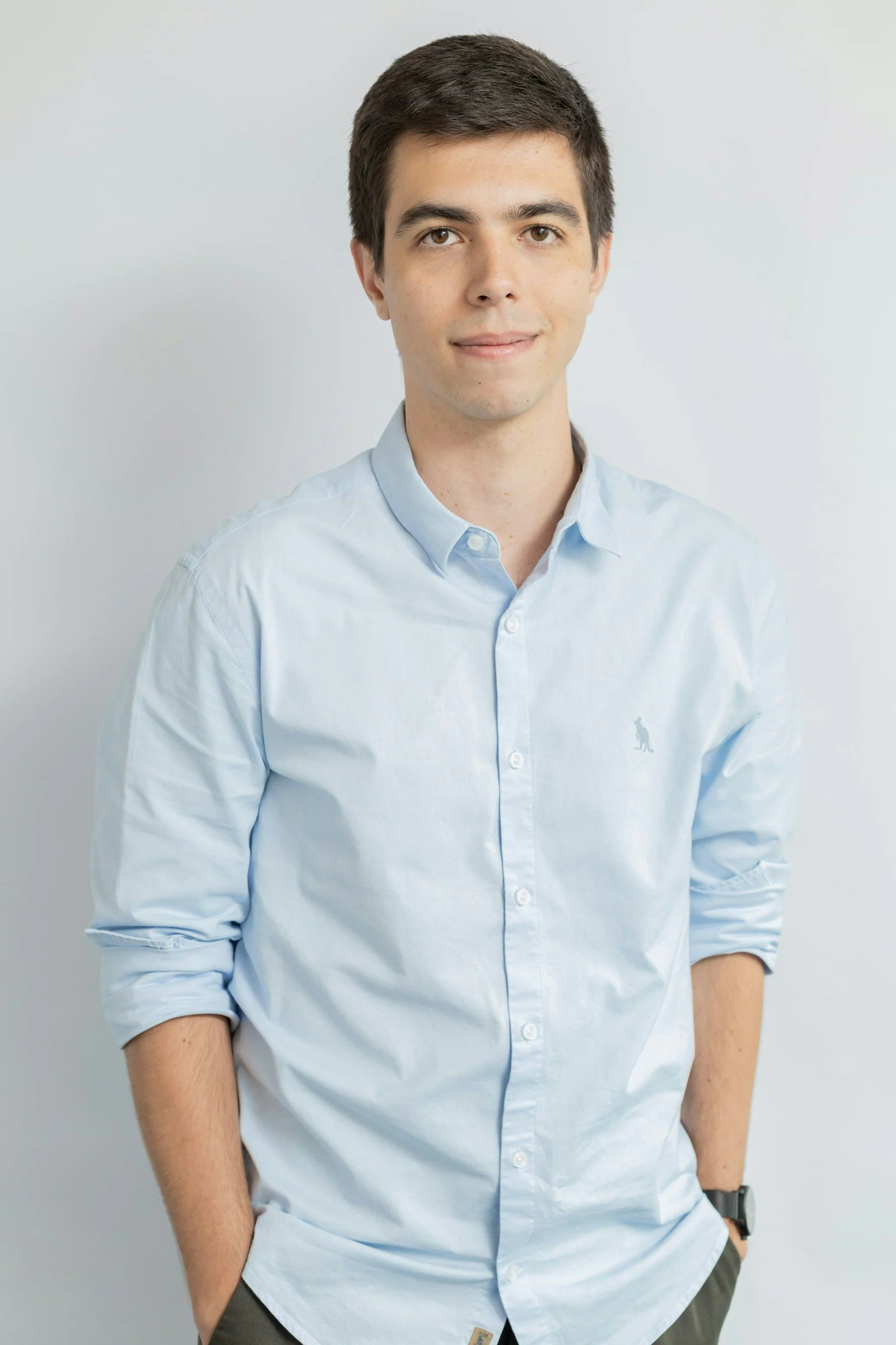 Young man in a light blue collared shirt smiling