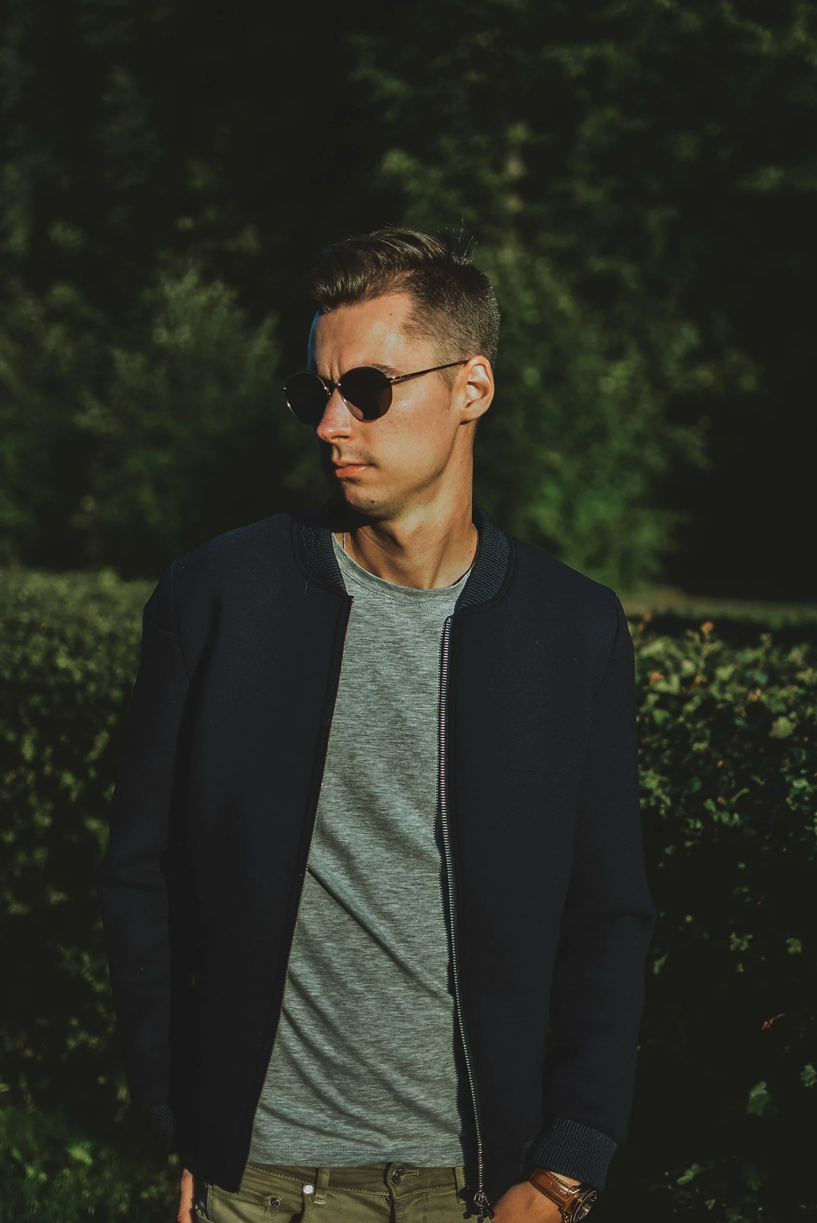Man in gray crew neck shirt and black cardigan wearing black sunglasses