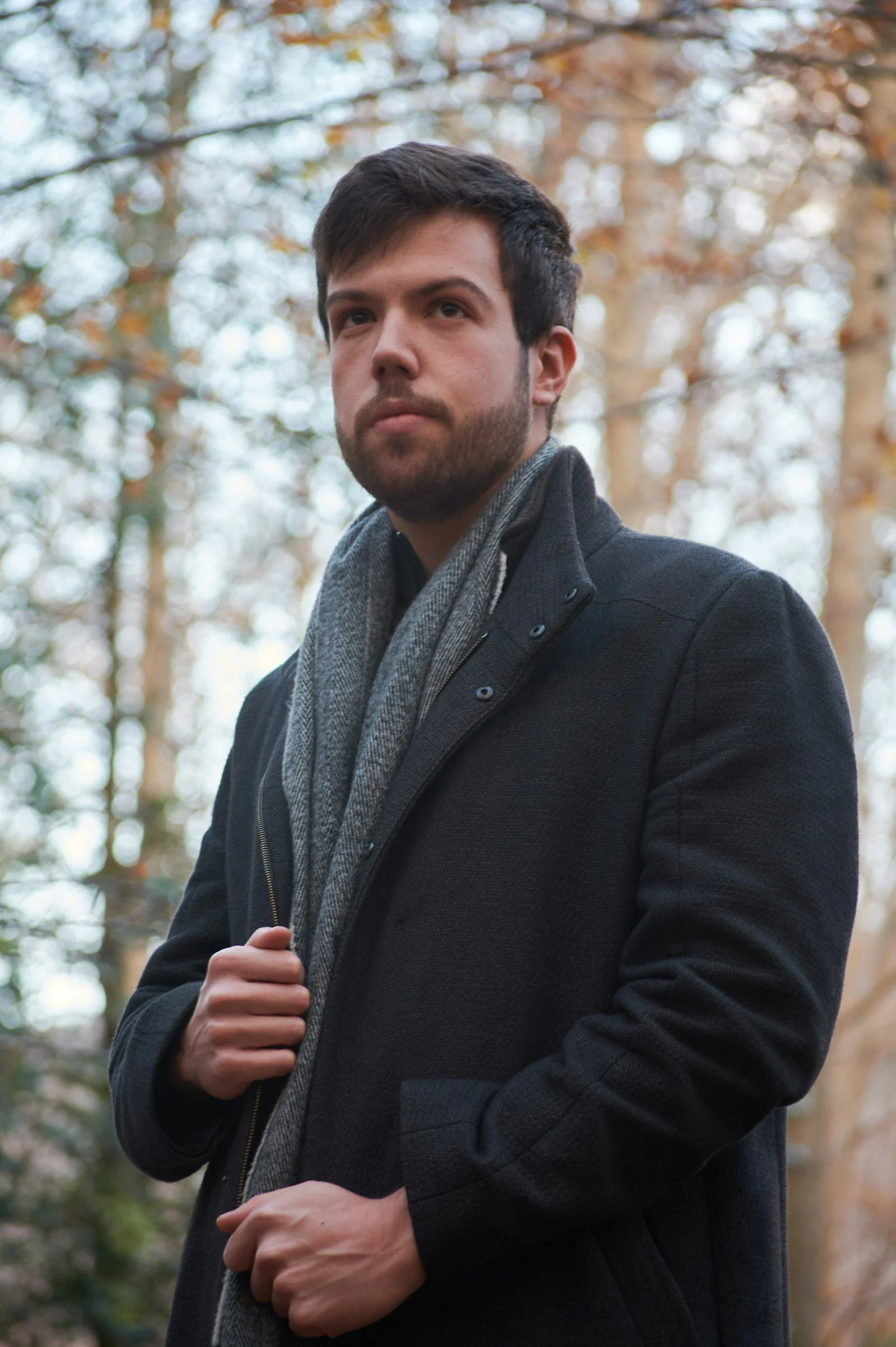 Man in black coat standing near trees during daytime