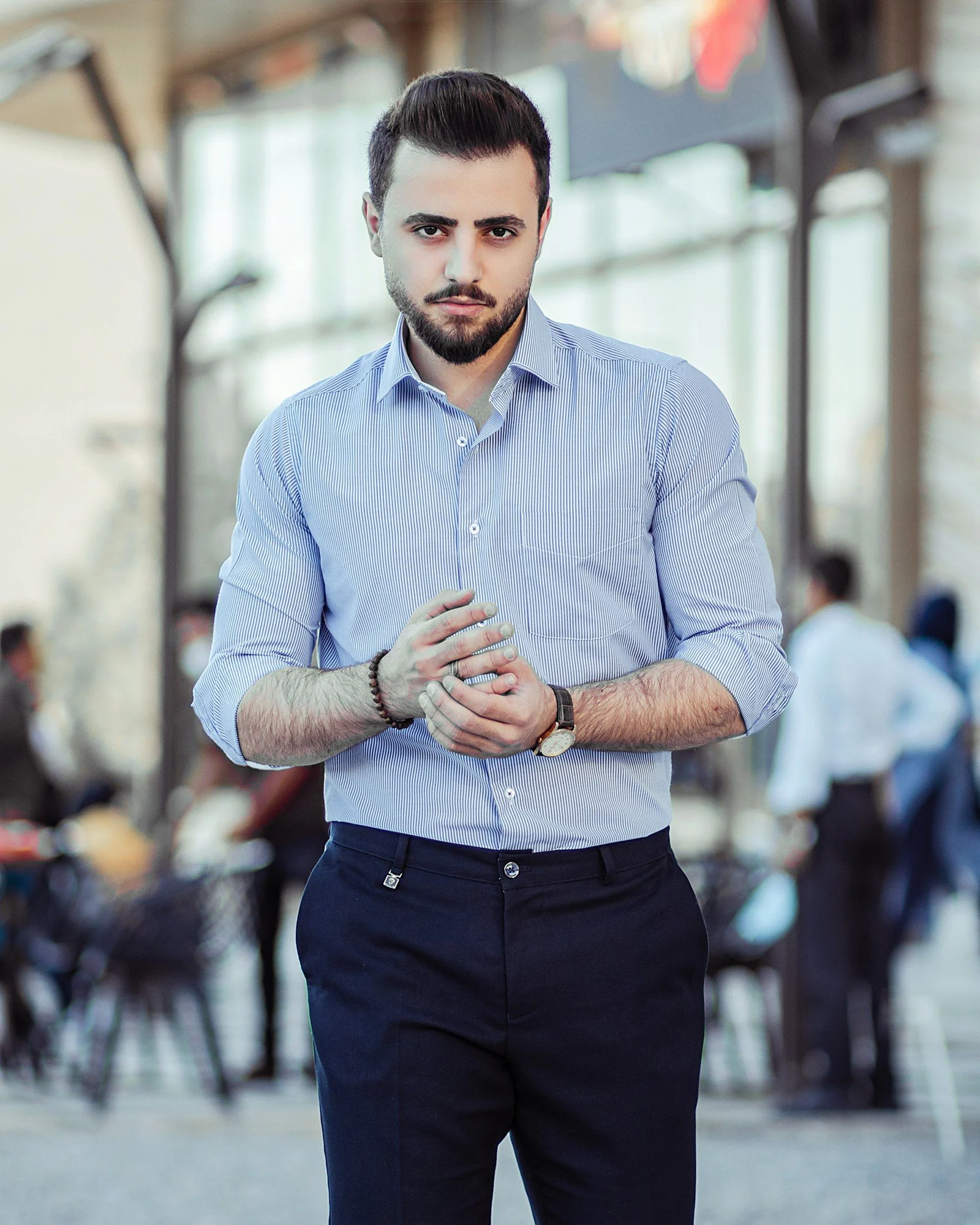 Man in blue dress shirt and black dress pants standing
