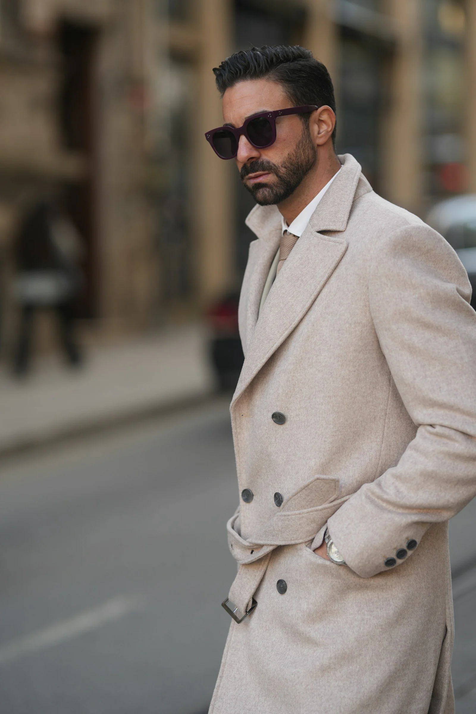 A man in a trench coat standing on a street corner
