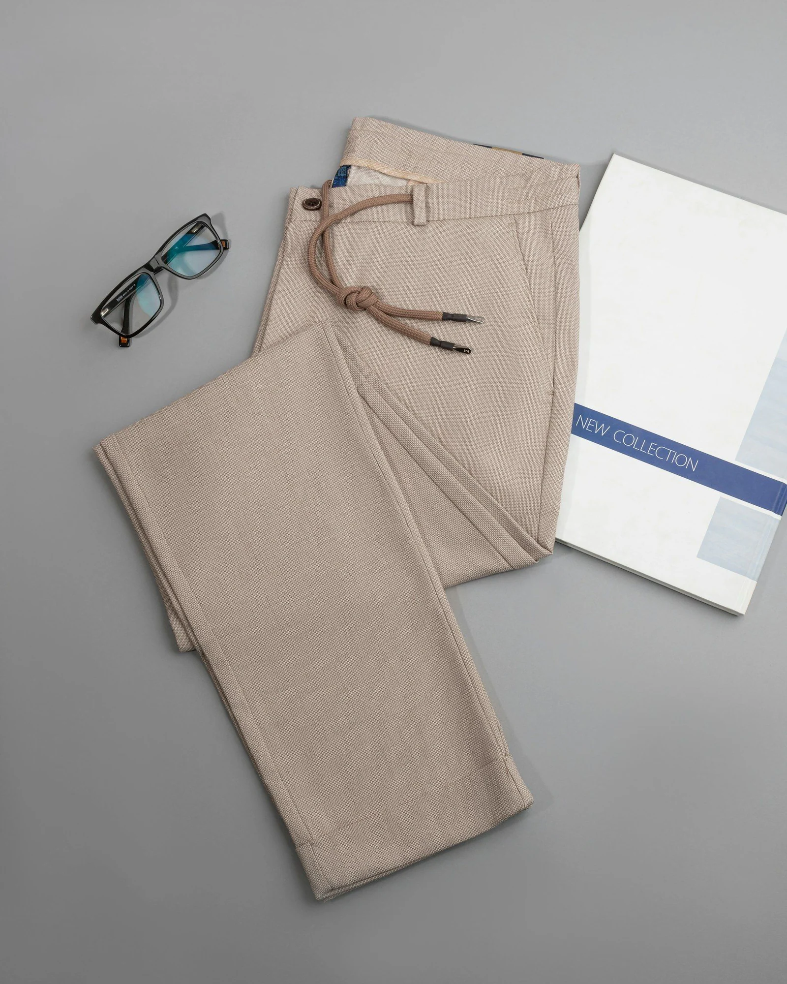 A pair of glasses a book and a pair of pants on a table