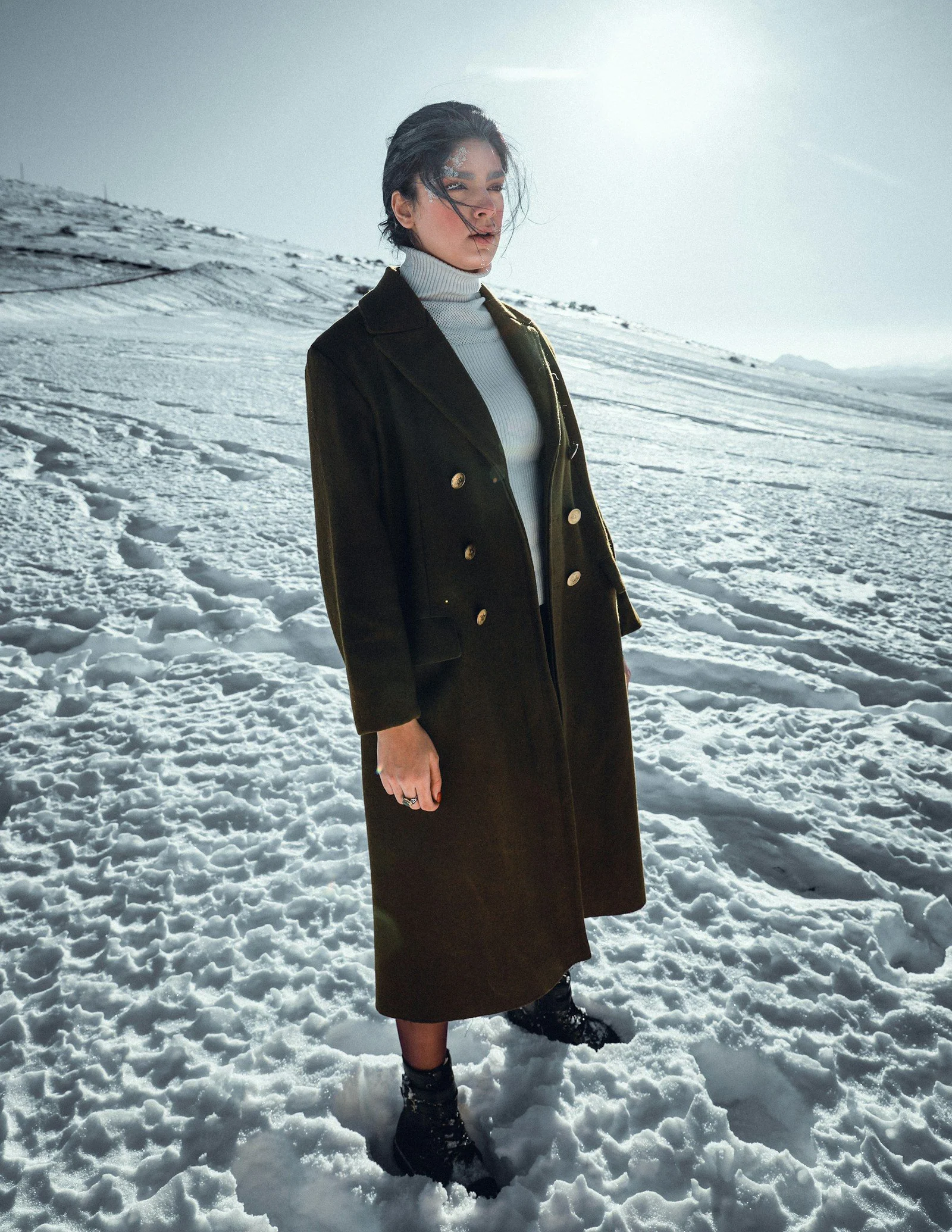 A woman standing in the snow wearing a coat