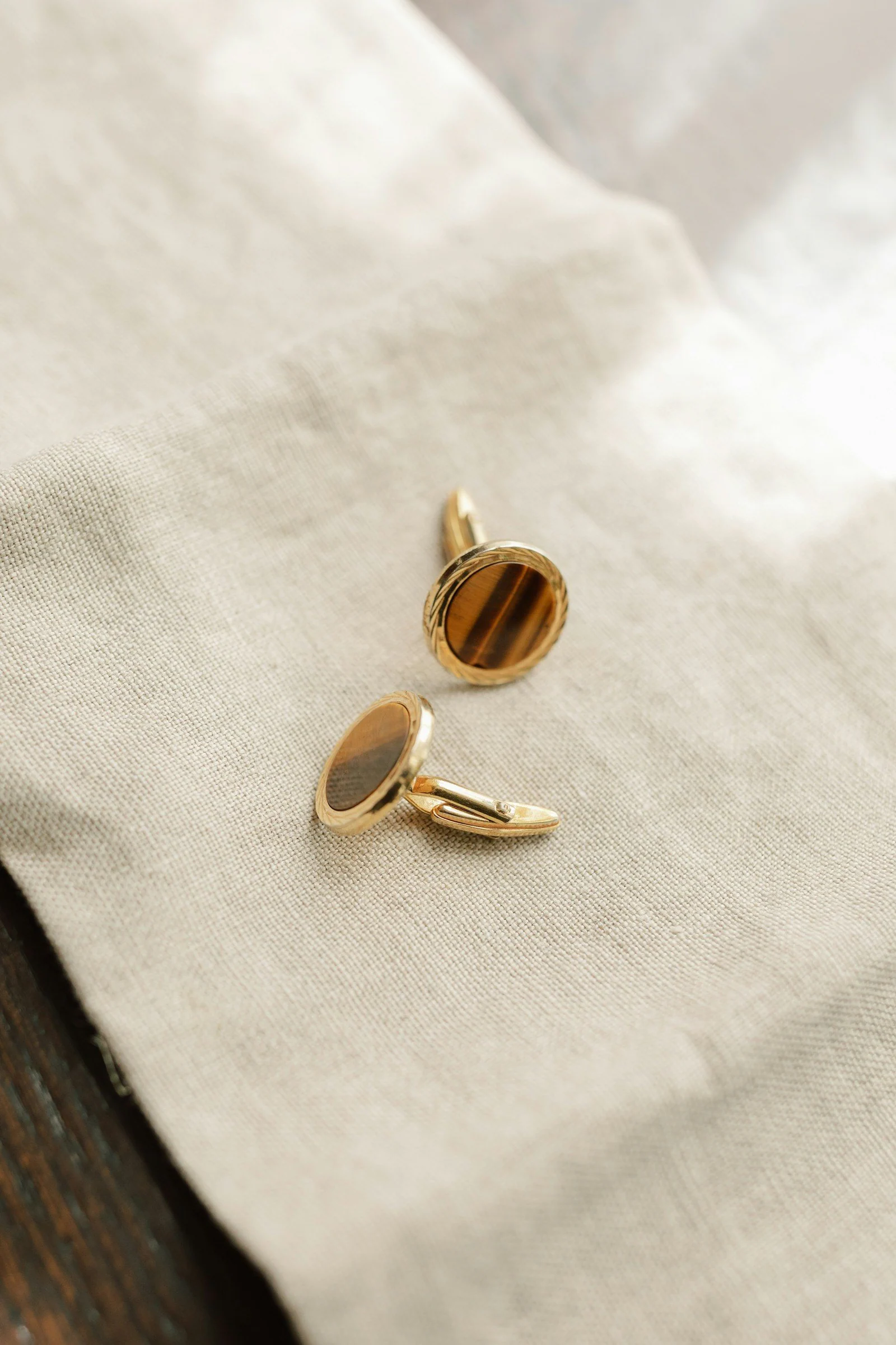 A pair of gold cufflinks sitting on top of a piece of cloth