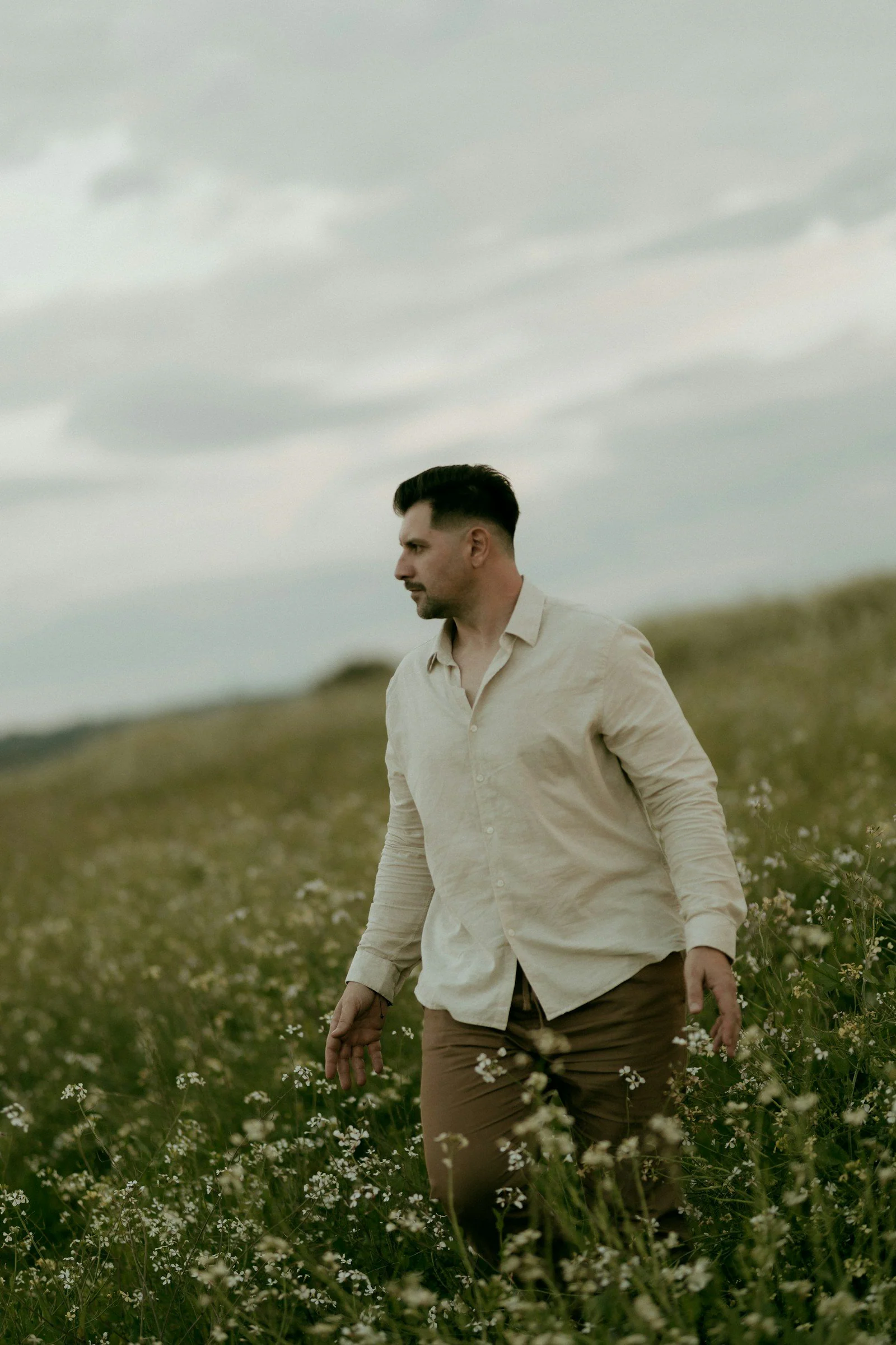 A man walks through a field of white flowers