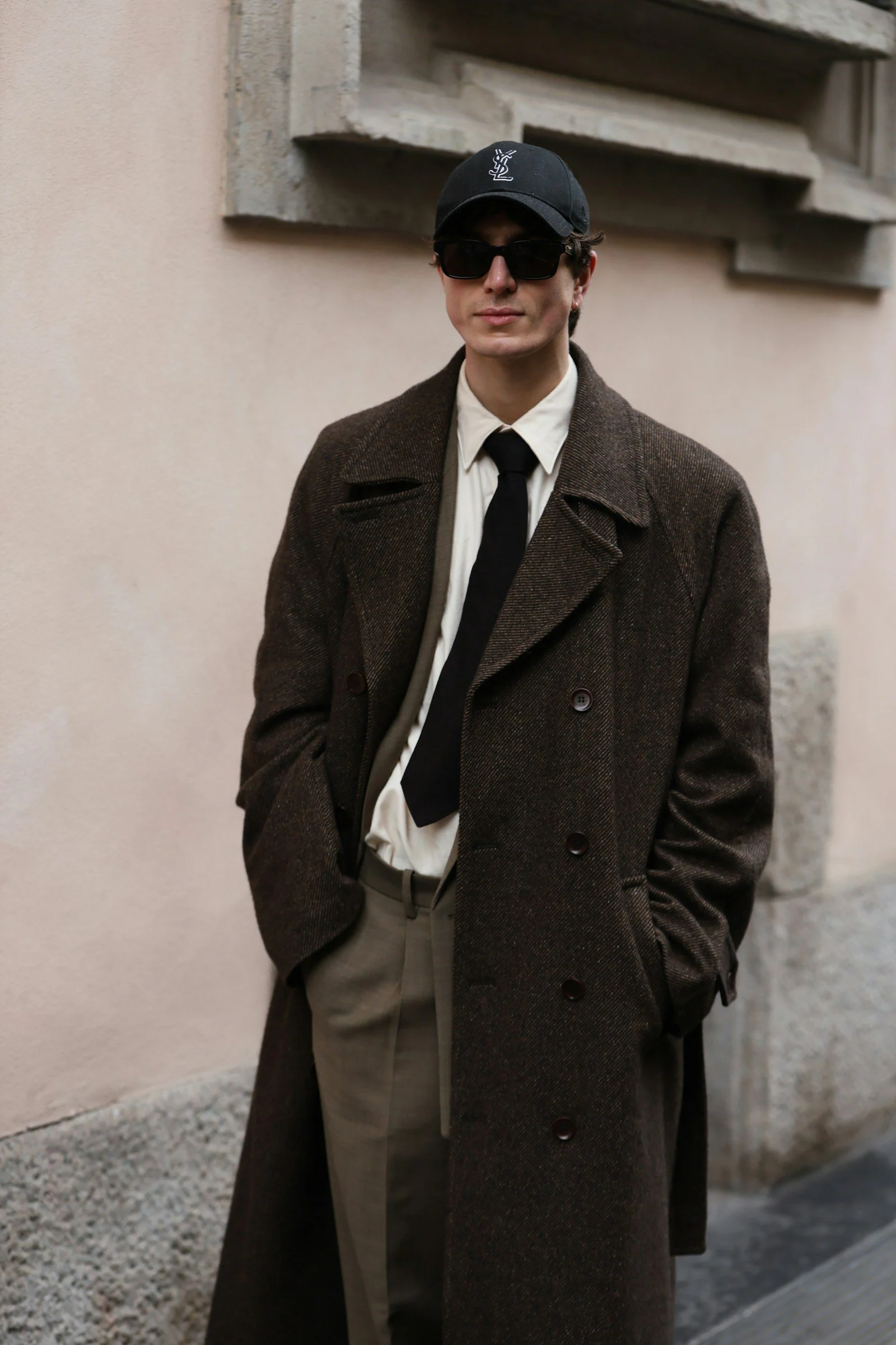A man in a coat and tie standing in front of a building