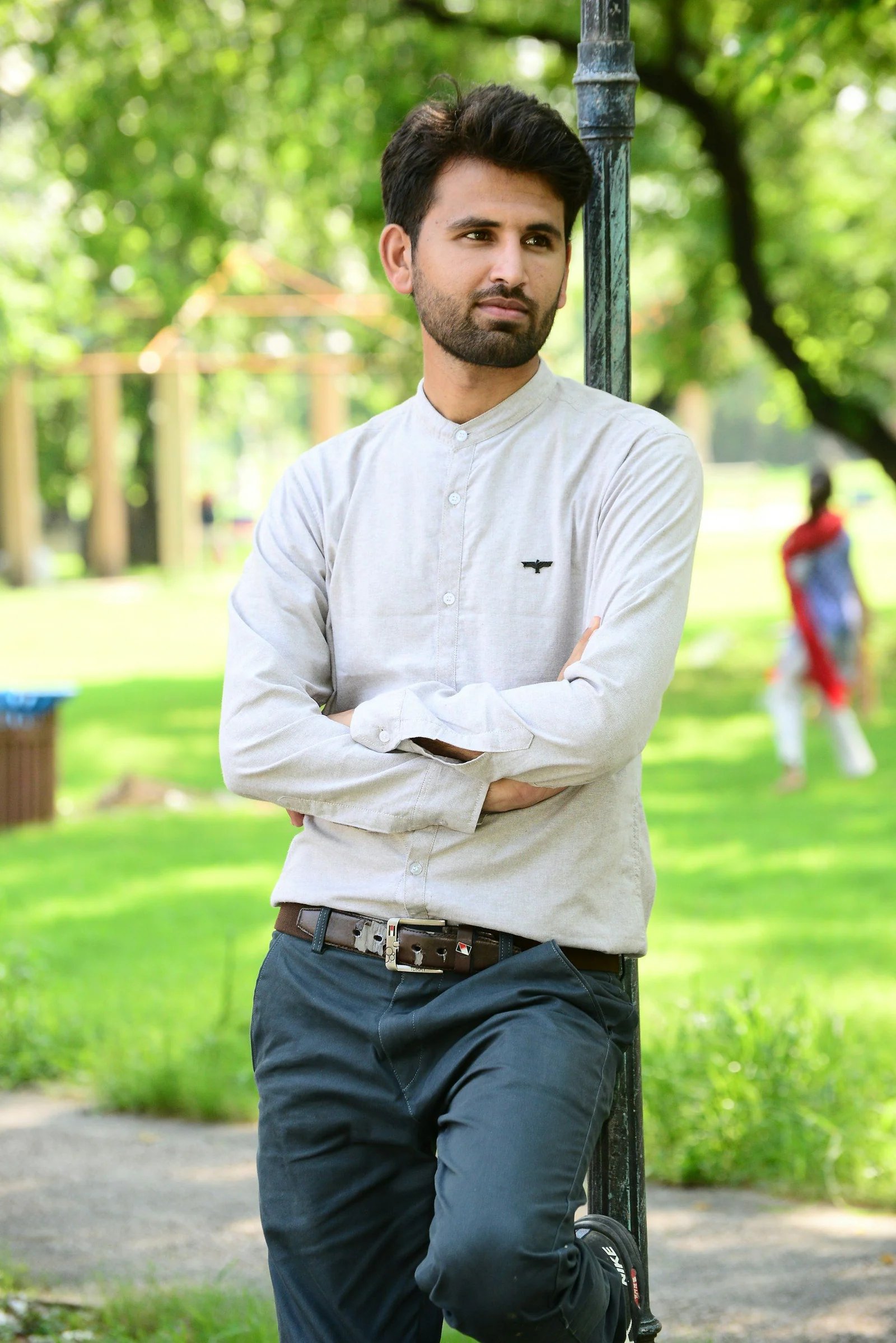 Man in white dress shirt and blue denim jeans standing on green grass field during daytime