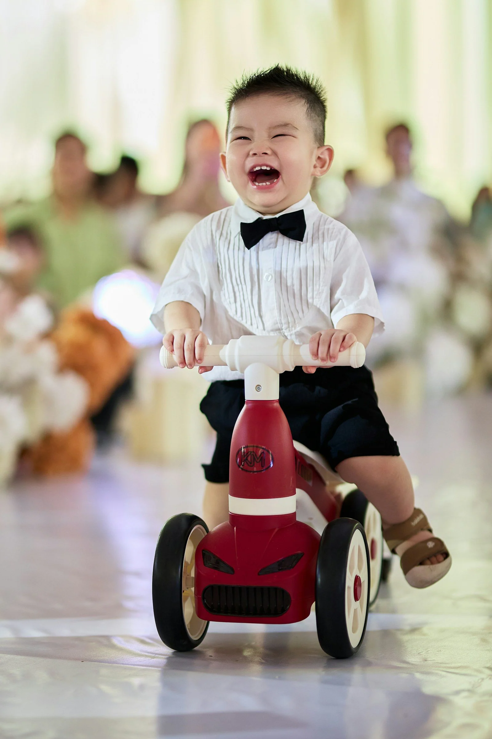 Laughing toddler riding red tricycle