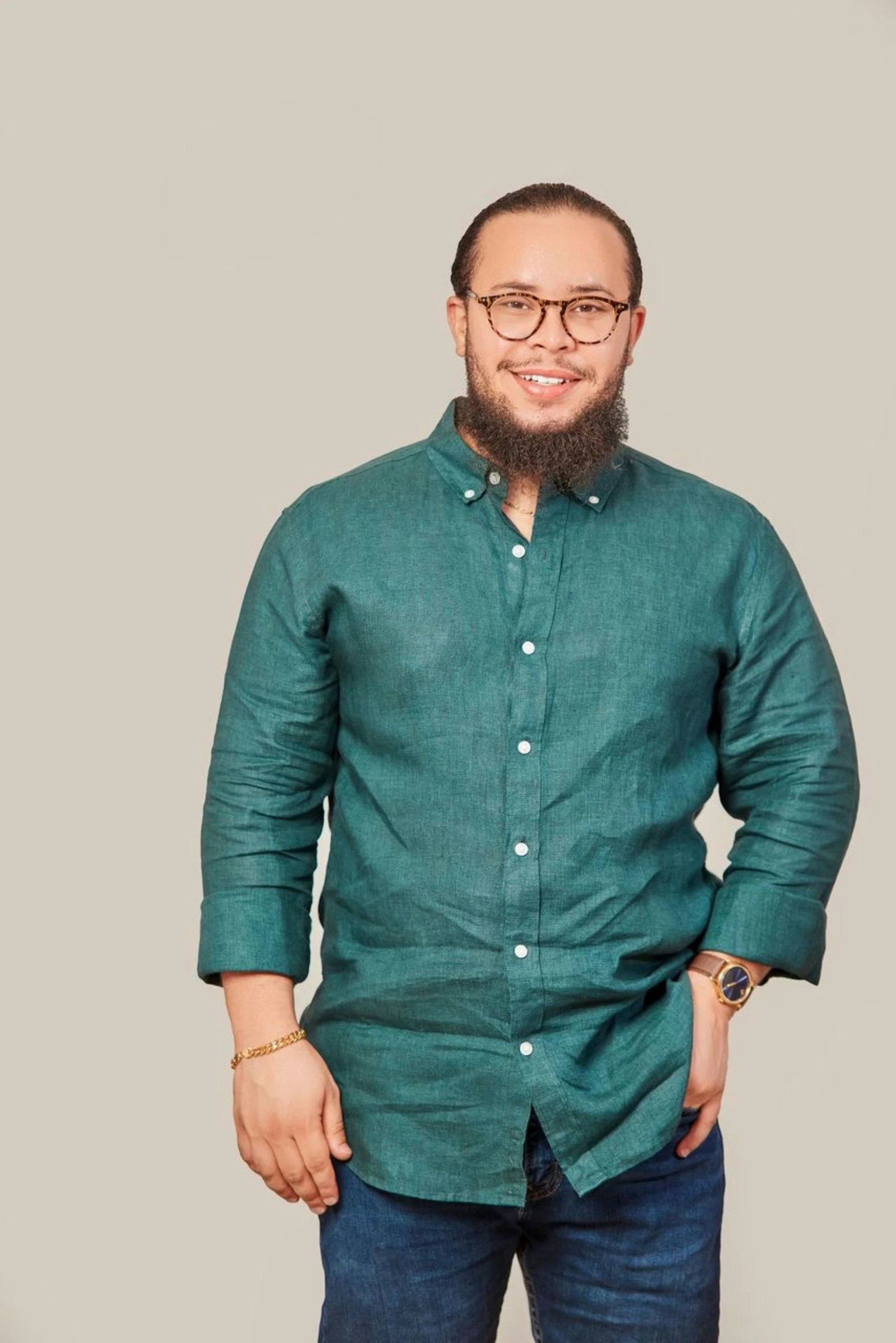 A smiling man with a beard glasses and green shirt
