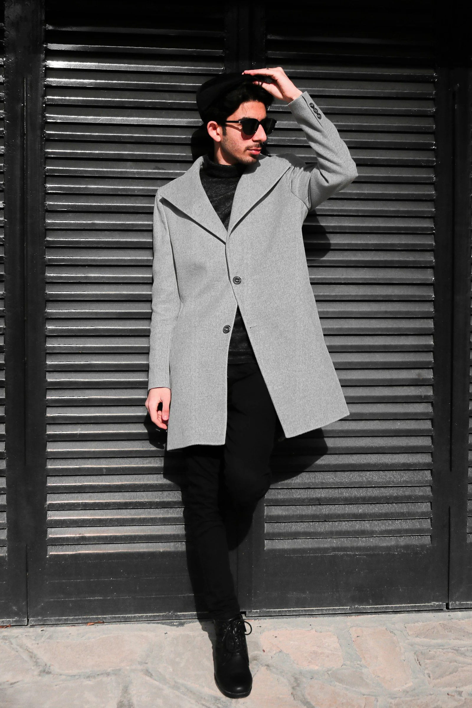 A man wearing a gray coat and black pants