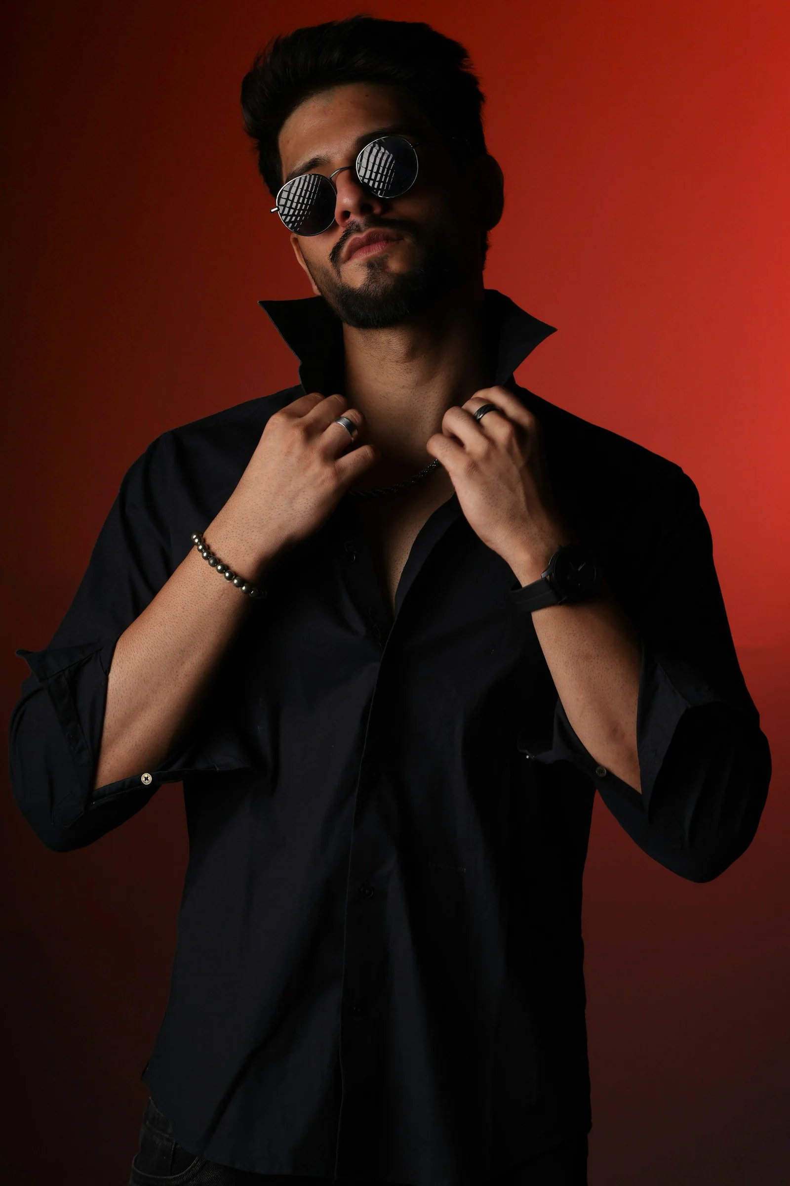 A stylish man in a black shirt and round sunglasses