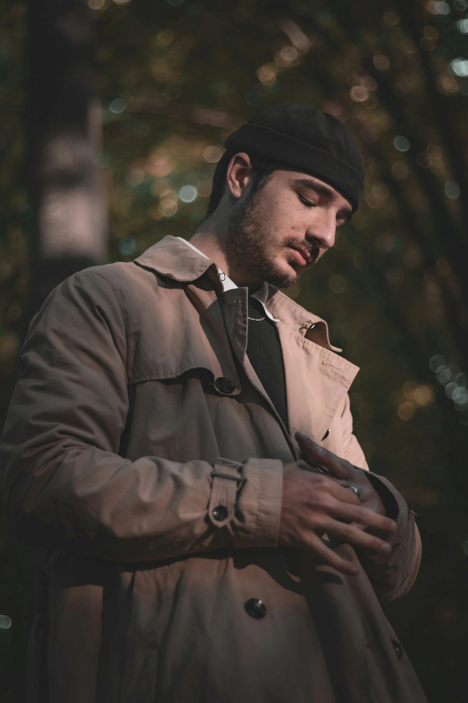 A man in a trench coat looking at his cell phone