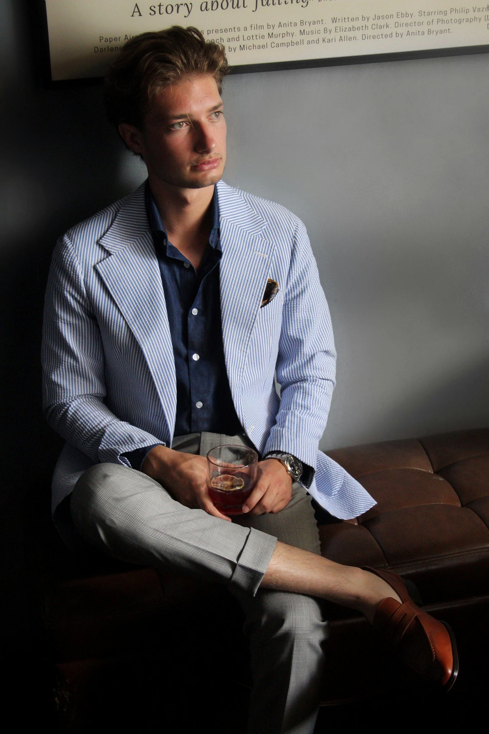 Man in light blue seersucker jacket holding drink