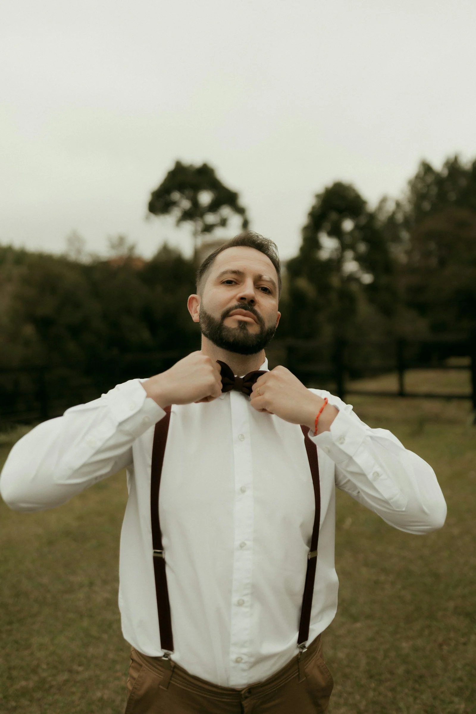 Stylish man adjusting his bow tie outdoors