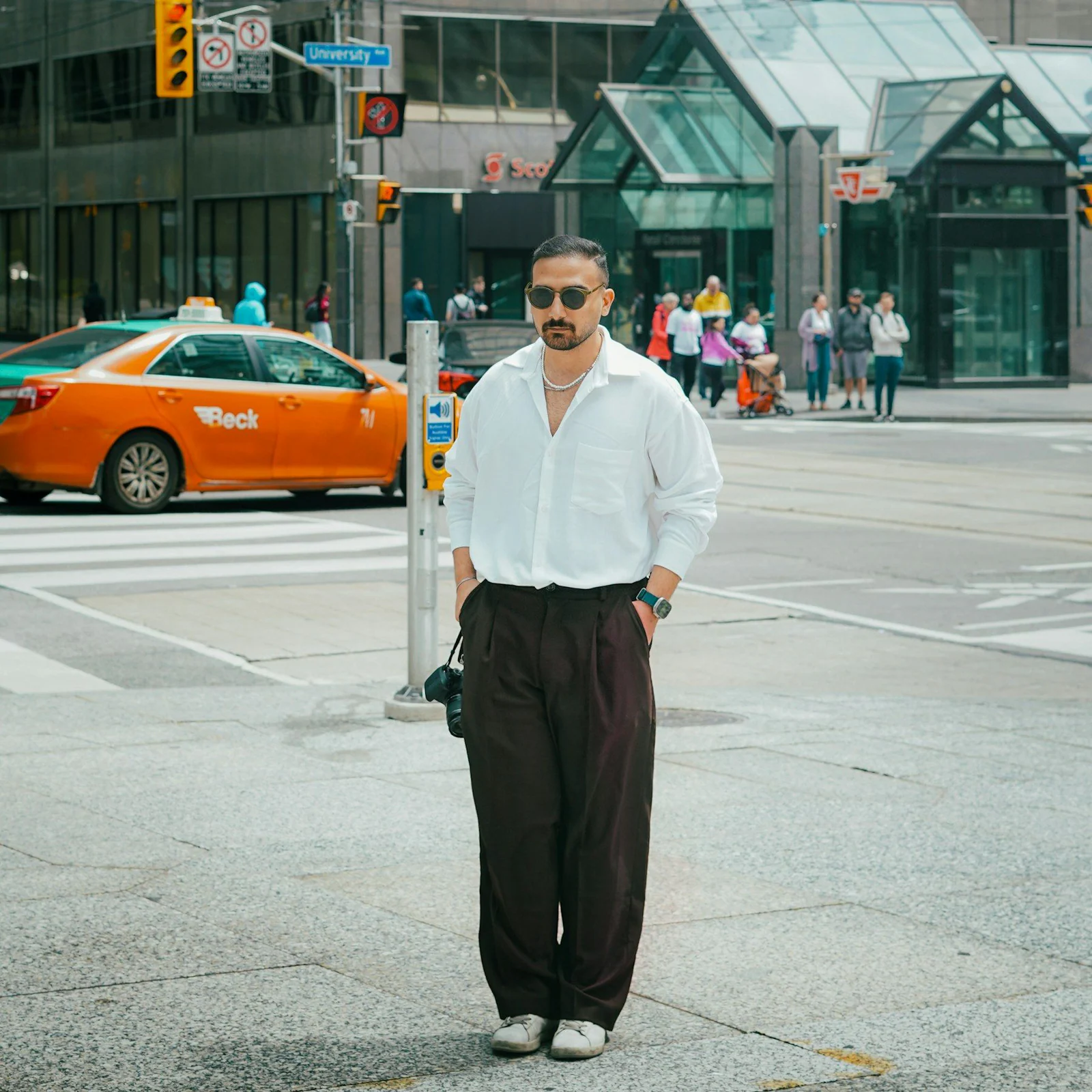 A man standing on the side of a street next to a traffic light