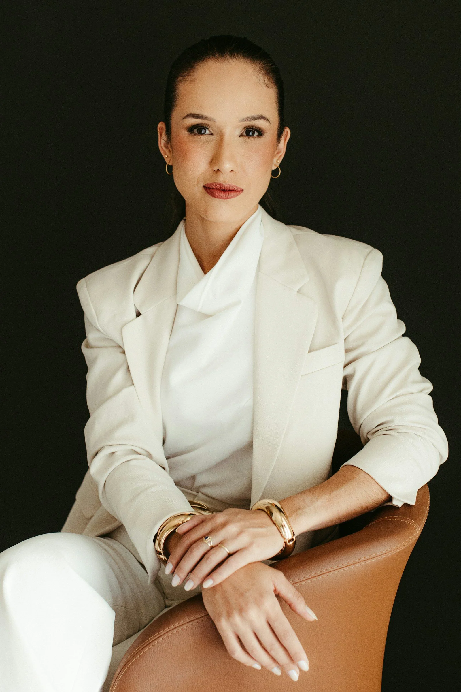Elegant woman in white suit against a dark background