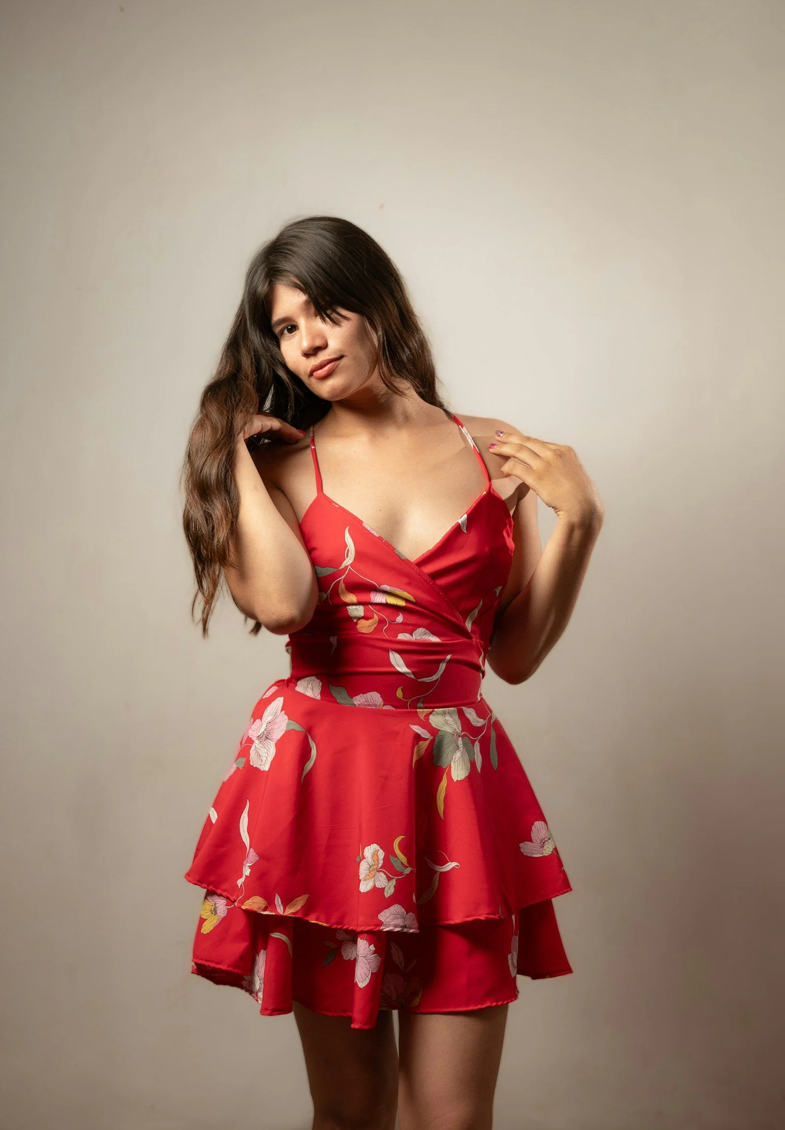 A woman poses in a red floral dress
