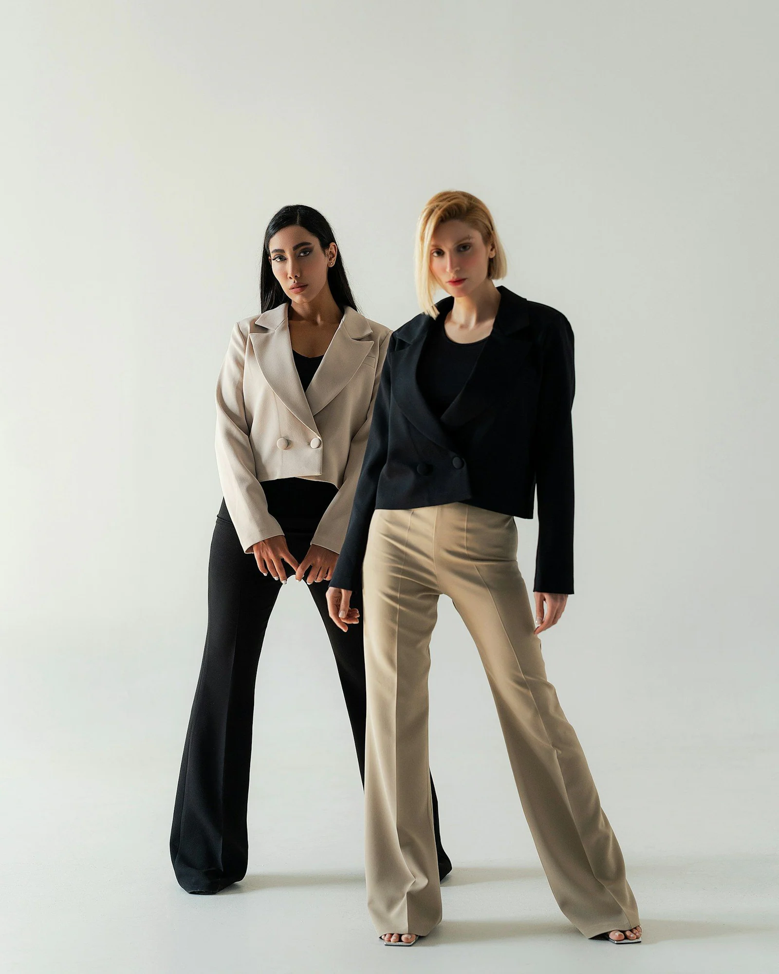 Two women standing next to each other in front of a white background