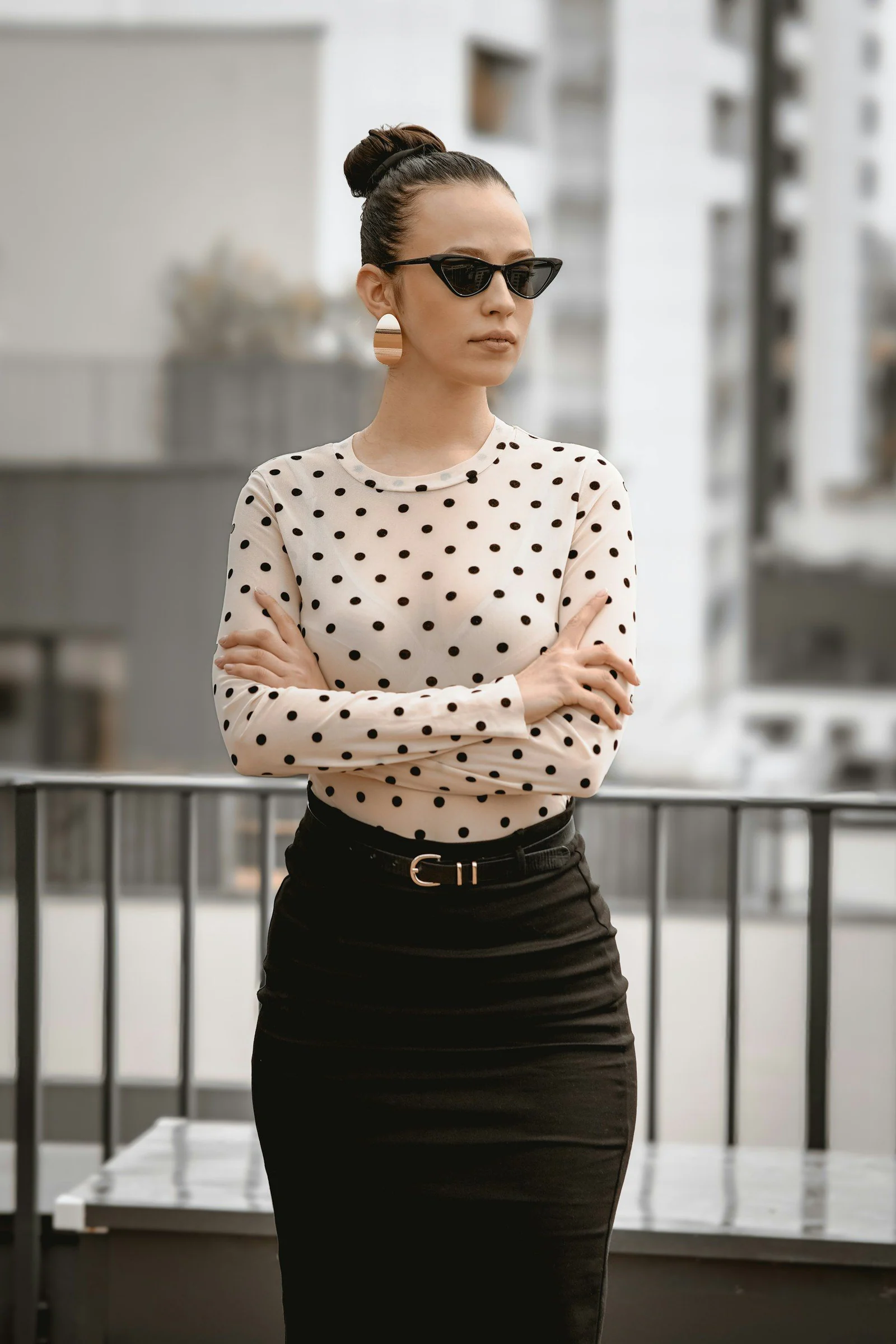 Stylish woman with crossed arms wearing sunglasses and polka dots