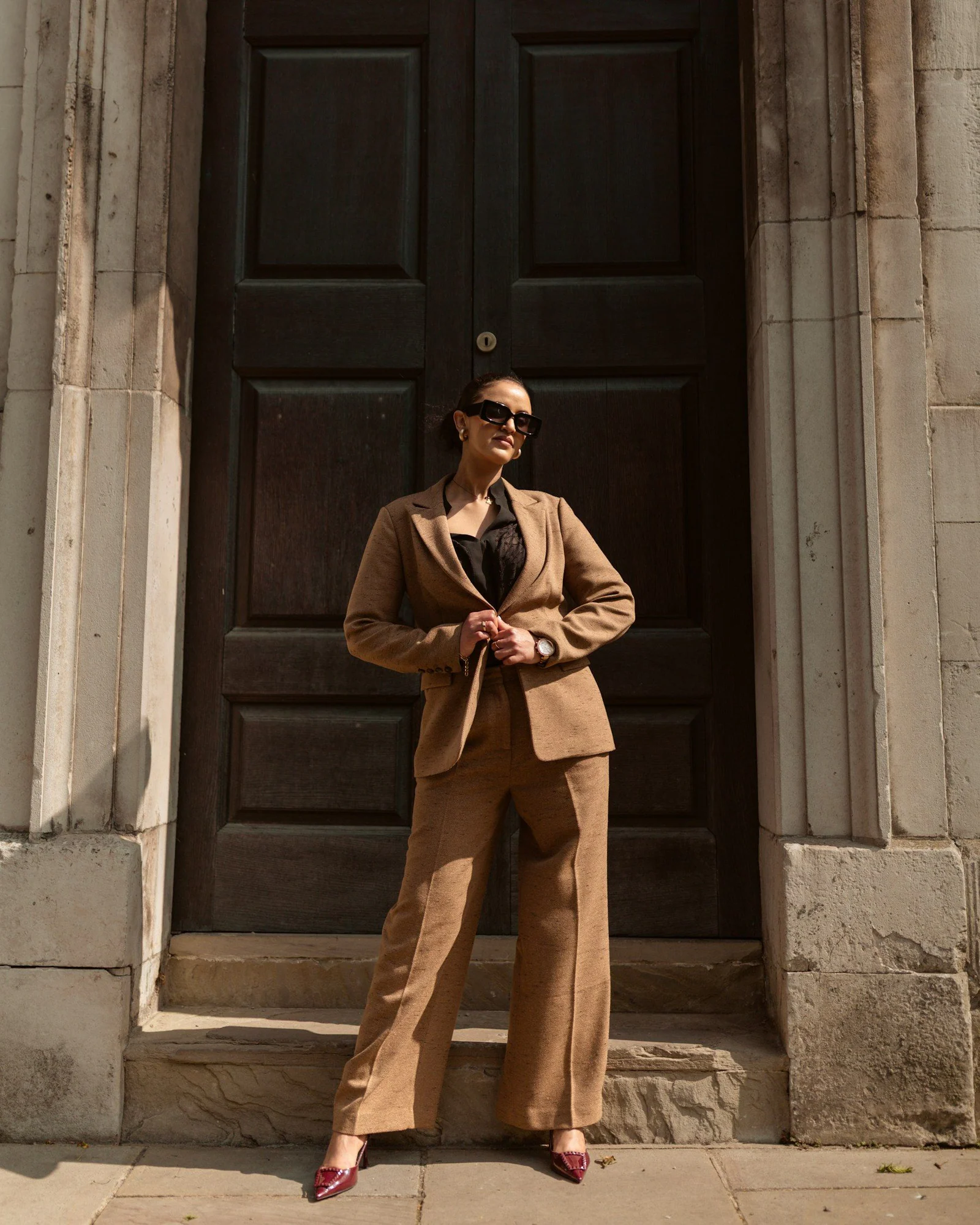 A stylish woman in a brown pantsuit poses