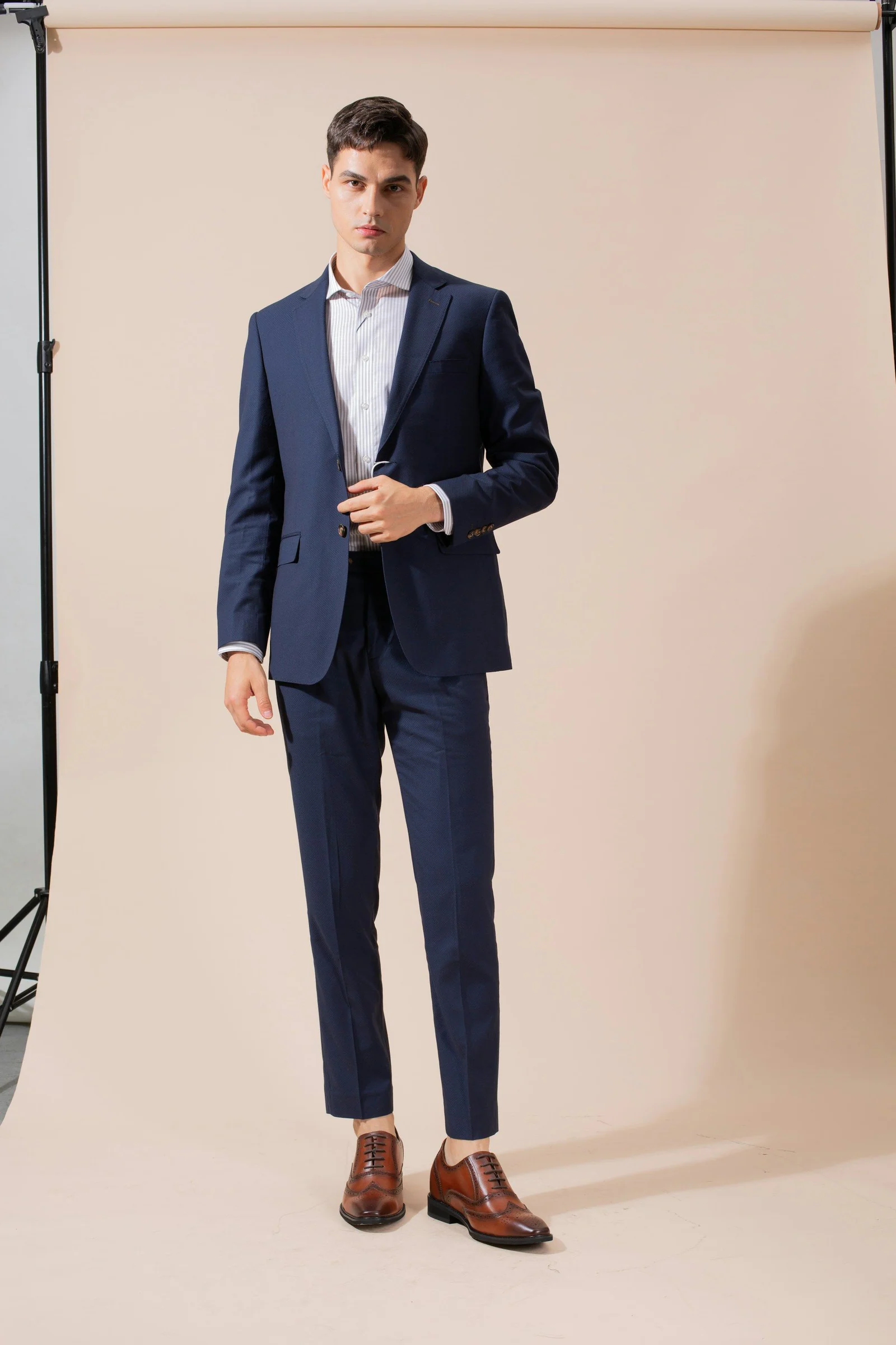 Navy business suit, full length, against a studio backdrop