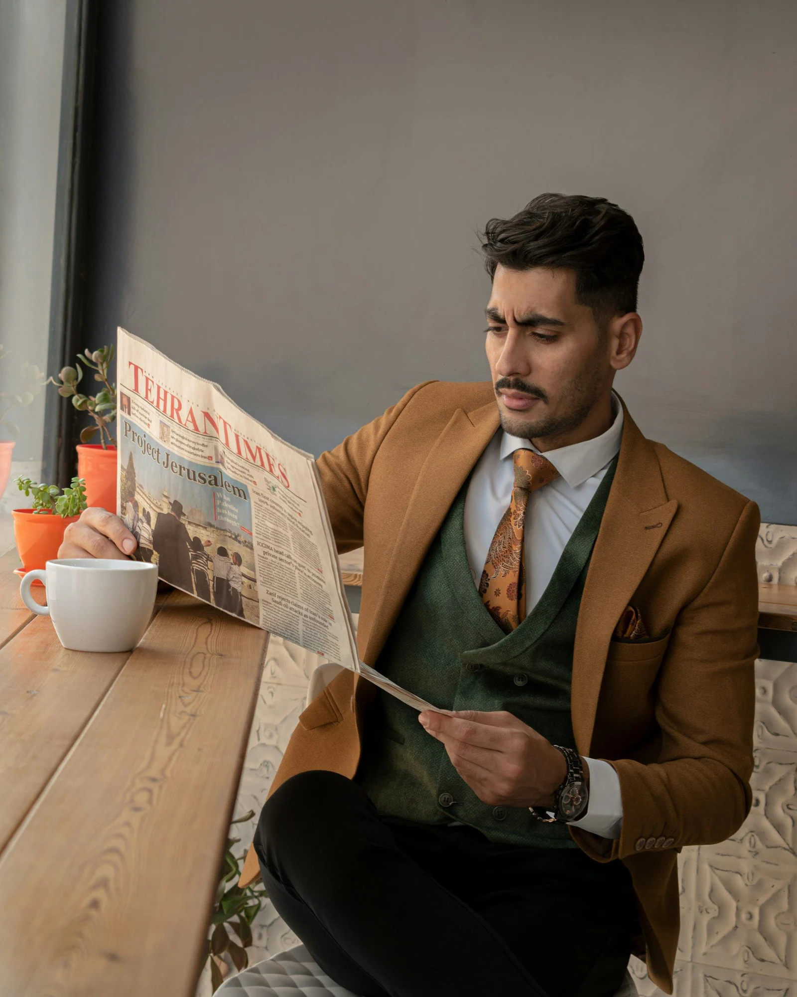 Rust jacket and green waistcoat, reading at a café table