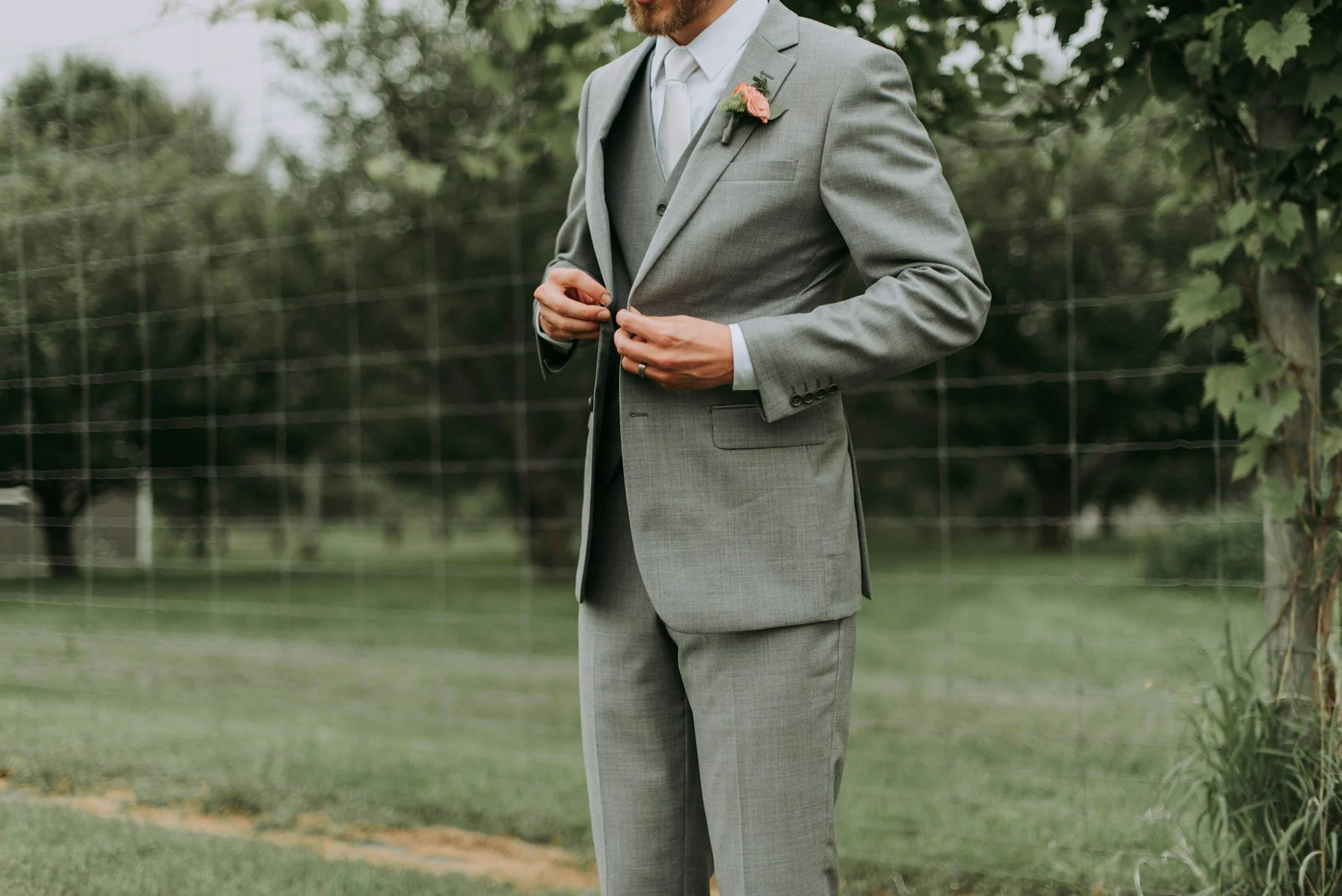Groom in a light grey suit with a buttonhole flower