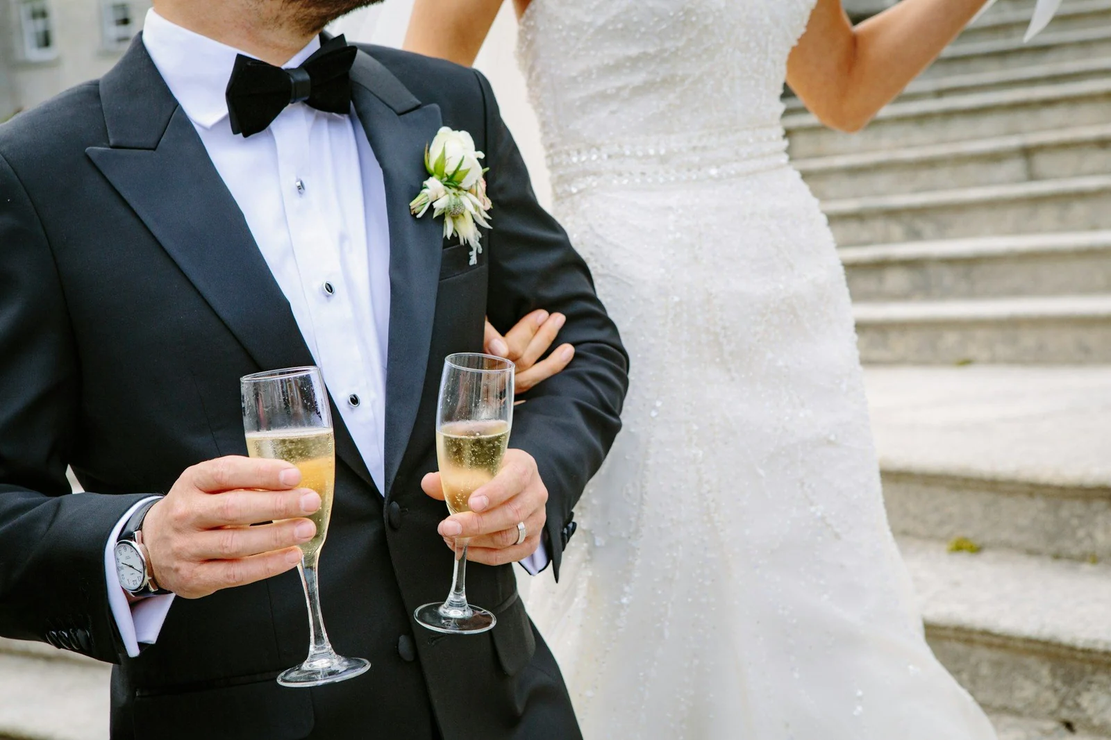 Groom in a dinner suit with champagne, beside the bride