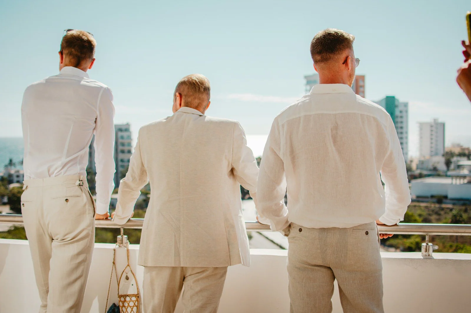 Groomsmen in cream suits on a balcony